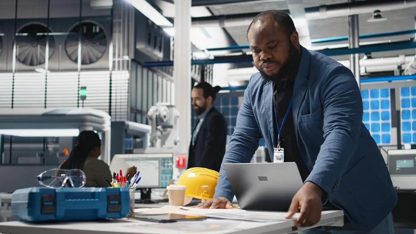 A Black solar panel engineer conducting an inspection in a high-tech facility.